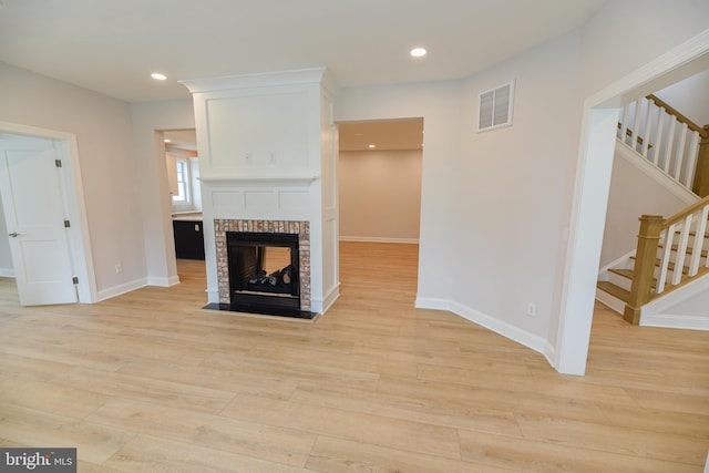 unfurnished living room featuring a brick fireplace and light hardwood / wood-style flooring