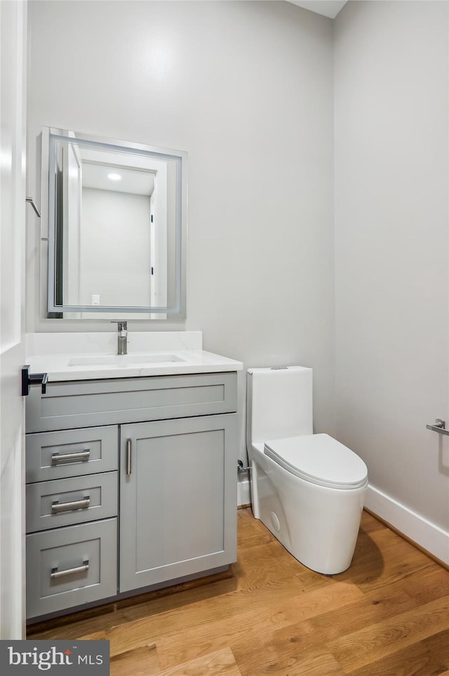 bathroom featuring vanity, wood finished floors, toilet, and baseboards