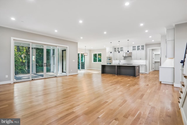 unfurnished living room featuring baseboards, light wood-style floors, stairs, and recessed lighting