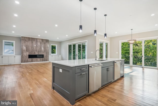 kitchen featuring gray cabinetry, a fireplace, a sink, light countertops, and dishwasher