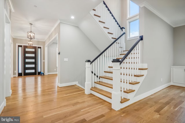 entrance foyer featuring baseboards, ornamental molding, an inviting chandelier, light wood-type flooring, and recessed lighting