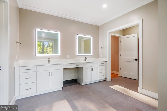 bathroom with double vanity, baseboards, ornamental molding, and a sink