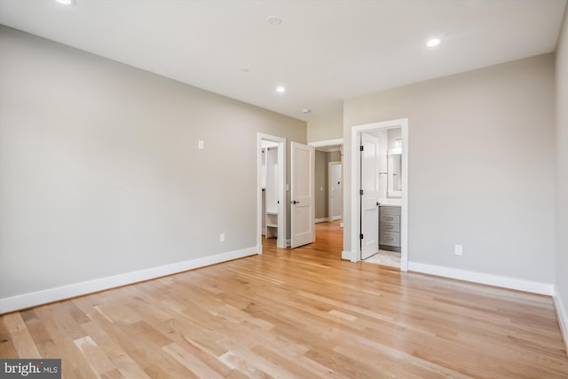 unfurnished bedroom with a walk in closet, recessed lighting, ensuite bath, light wood-type flooring, and baseboards