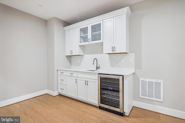 bar with wine cooler, baseboards, visible vents, and light wood finished floors