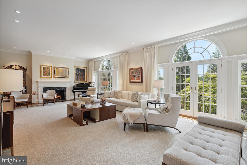 carpeted living room with crown molding, a fireplace, and french doors