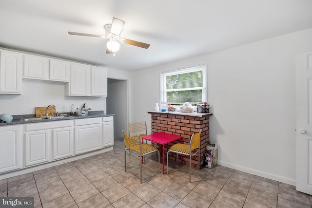 kitchen with light tile patterned floors, white cabinetry, ceiling fan, and sink