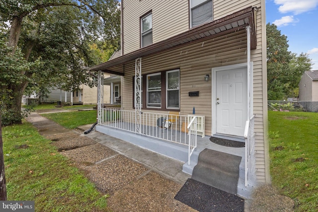 view of exterior entry featuring a porch and a yard