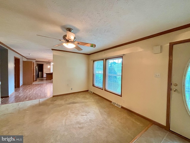 interior space featuring a textured ceiling, light colored carpet, ceiling fan, and ornamental molding