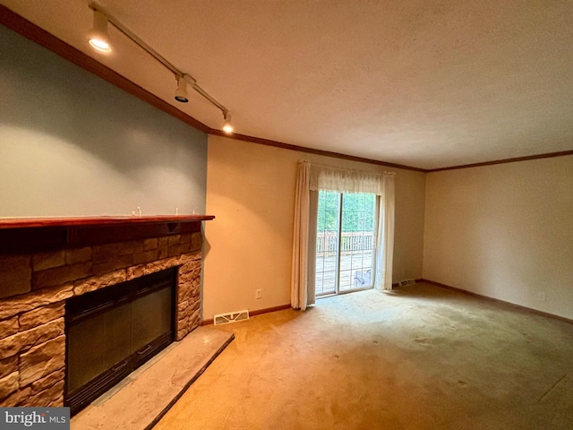 unfurnished living room featuring track lighting, ornamental molding, a textured ceiling, light colored carpet, and a fireplace