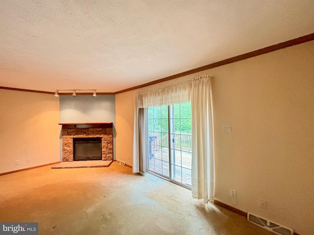 unfurnished living room featuring a fireplace, carpet, a textured ceiling, and ornamental molding