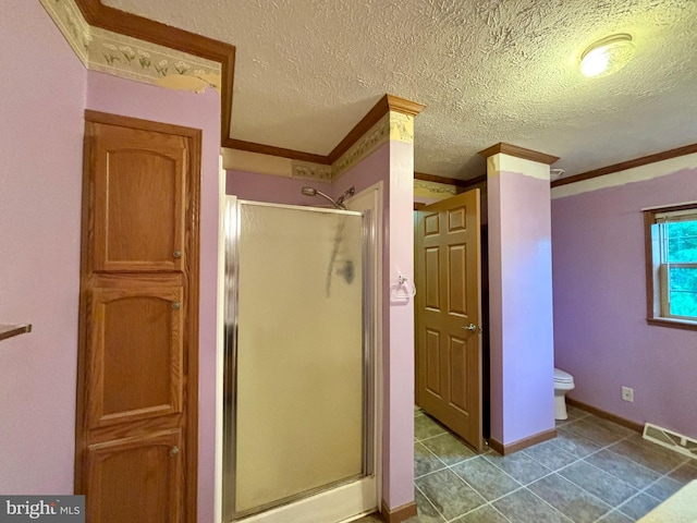 bathroom with tile patterned flooring, decorative columns, a textured ceiling, a shower with shower door, and ornamental molding