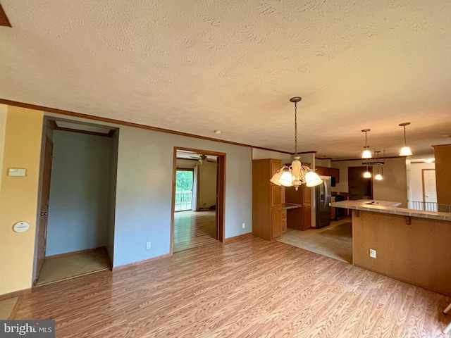 interior space with hanging light fixtures, light hardwood / wood-style flooring, kitchen peninsula, crown molding, and a chandelier