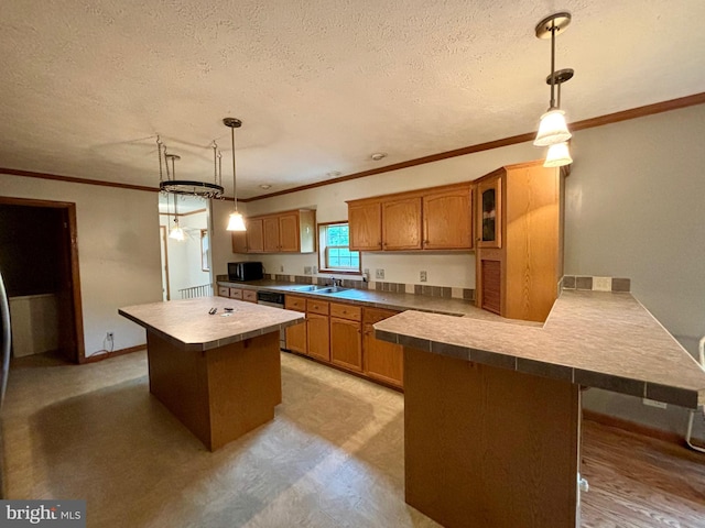 kitchen featuring a textured ceiling, sink, decorative light fixtures, and ornamental molding