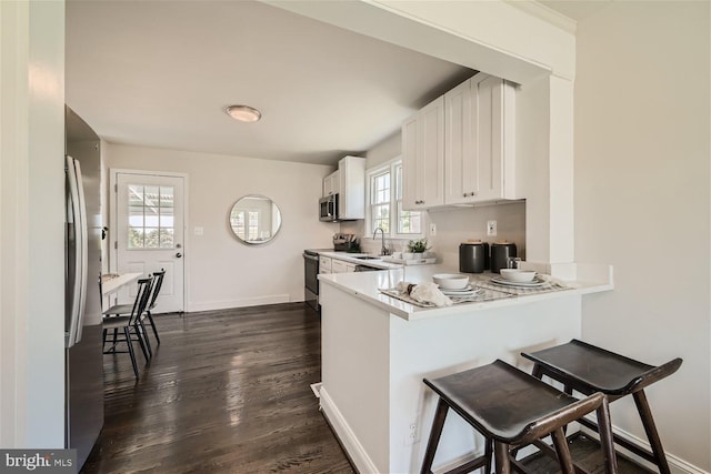 kitchen with kitchen peninsula, appliances with stainless steel finishes, a breakfast bar, and plenty of natural light