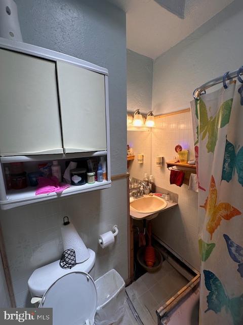 bathroom featuring a shower with shower curtain, toilet, and sink