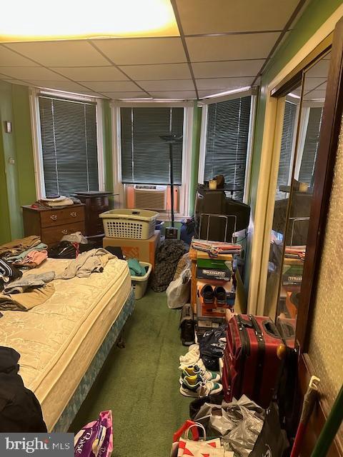 carpeted bedroom with a paneled ceiling and cooling unit