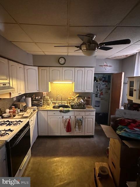 kitchen with a drop ceiling, white appliances, extractor fan, sink, and white cabinets