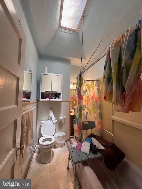 bathroom with curtained shower, vaulted ceiling, and toilet