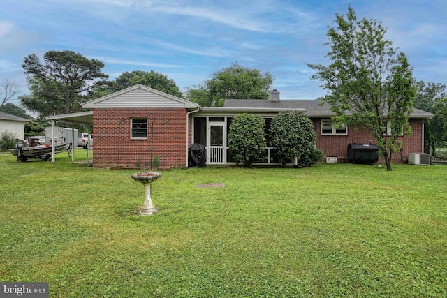 back of property featuring a yard, central AC unit, a carport, and a sunroom