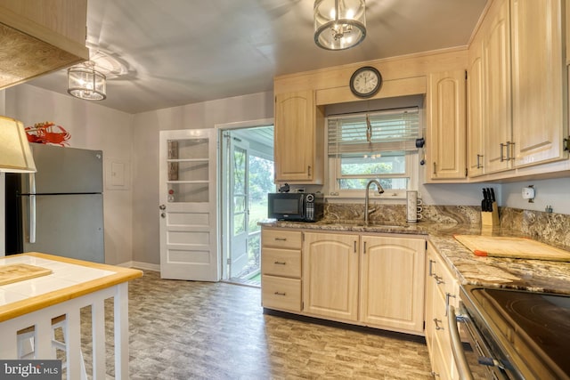 kitchen featuring light stone countertops, stainless steel fridge, light brown cabinetry, and sink