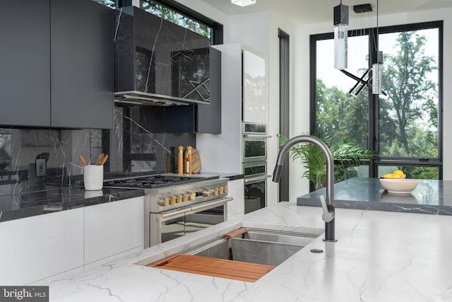 kitchen featuring sink, ventilation hood, backsplash, stone countertops, and high end stainless steel range