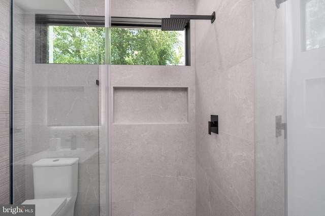 bathroom featuring tiled shower, plenty of natural light, tile walls, and toilet