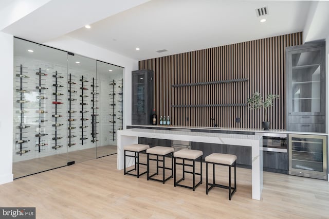 kitchen with a kitchen breakfast bar, light wood-type flooring, and wine cooler