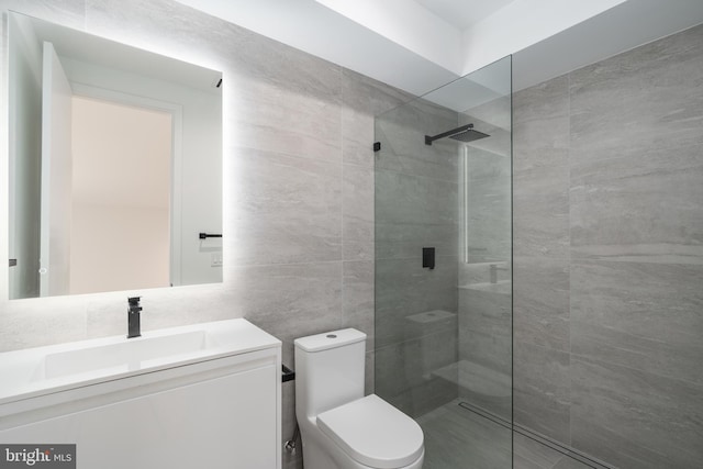 bathroom with vanity, toilet, tiled shower, and tile walls