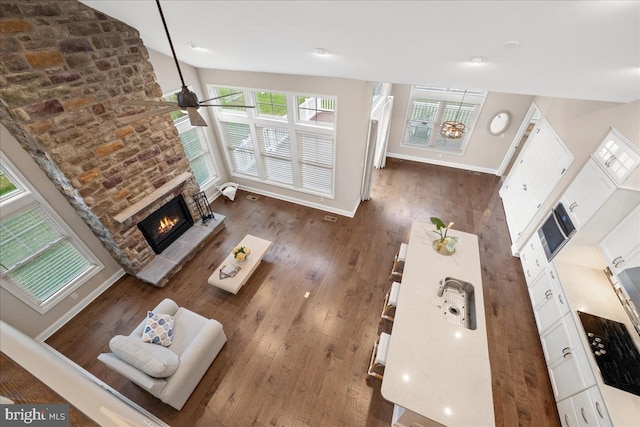 living room featuring ceiling fan, dark hardwood / wood-style flooring, and a fireplace