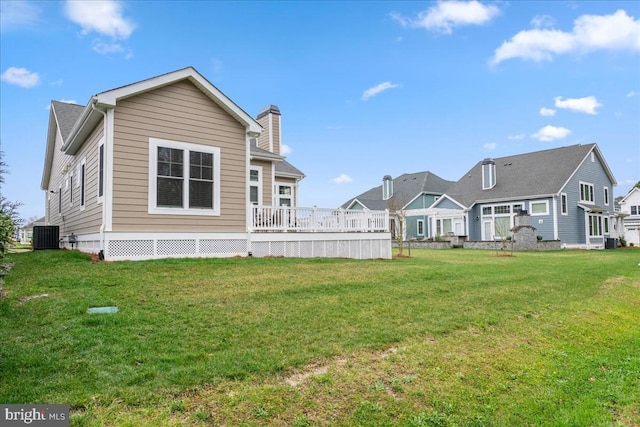 rear view of property with central AC unit, a wooden deck, and a lawn