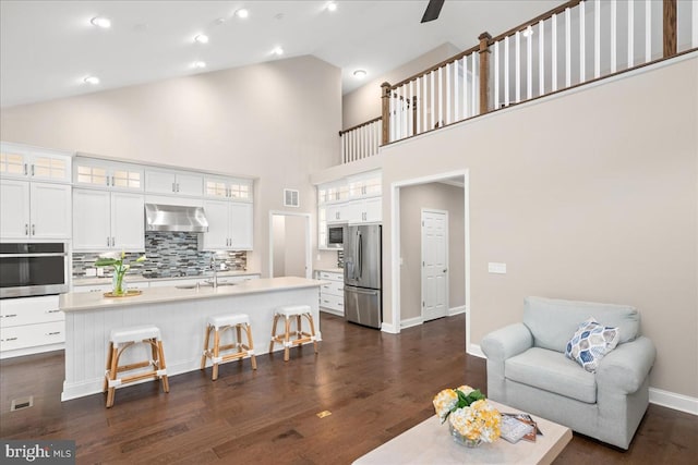 living room with dark hardwood / wood-style floors, high vaulted ceiling, and sink