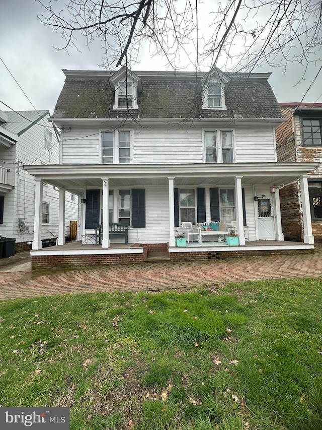 rear view of house featuring covered porch and a yard