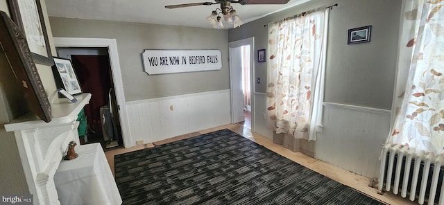 entrance foyer featuring tile patterned floors, ceiling fan, radiator heating unit, and wooden walls