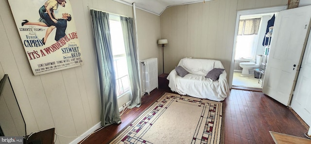 living area featuring radiator, wood walls, dark hardwood / wood-style floors, and ornamental molding