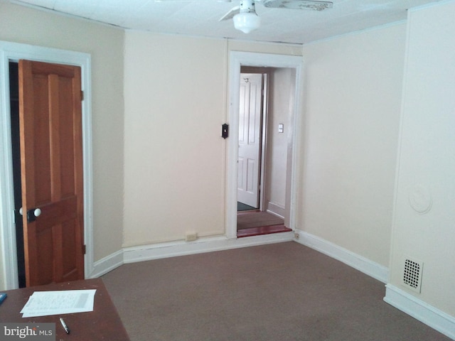 spare room featuring ceiling fan and dark carpet