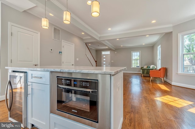 kitchen with a wealth of natural light, white cabinetry, hanging light fixtures, and wine cooler