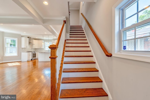 staircase with crown molding and wood-type flooring