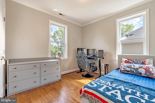 bedroom with multiple windows, crown molding, and light hardwood / wood-style floors