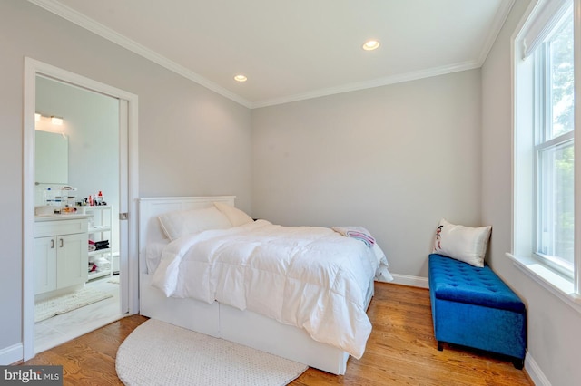 bedroom with multiple windows, crown molding, ensuite bath, and light wood-type flooring