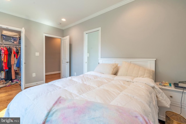 bedroom with crown molding, a walk in closet, light hardwood / wood-style flooring, and a closet