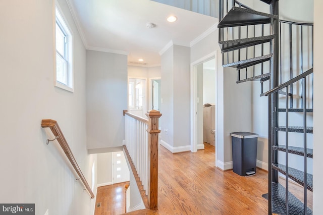 stairway with wood-type flooring and crown molding