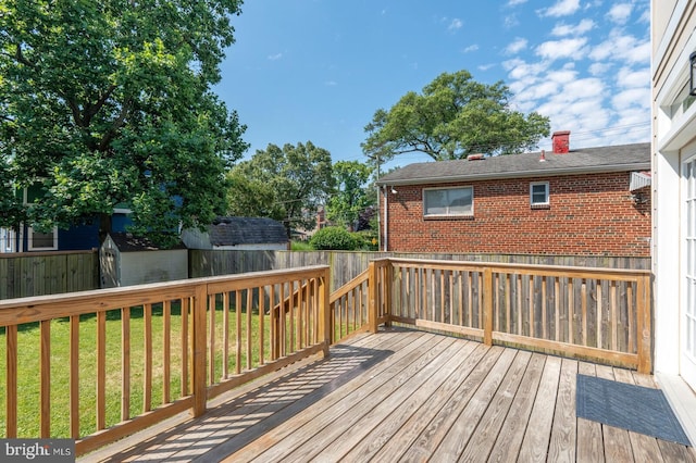 wooden terrace featuring a lawn and a storage unit