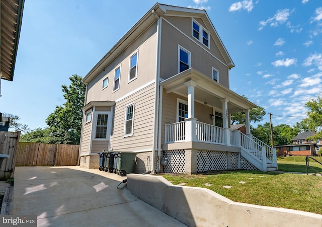 view of side of property featuring covered porch and a yard