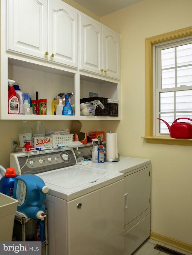 clothes washing area featuring cabinets and independent washer and dryer