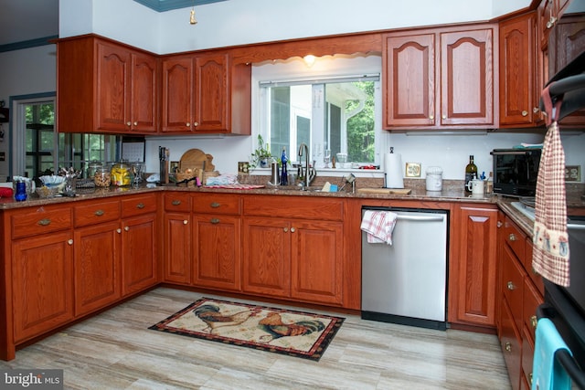 kitchen with ornamental molding, dark stone counters, sink, dishwasher, and light hardwood / wood-style floors