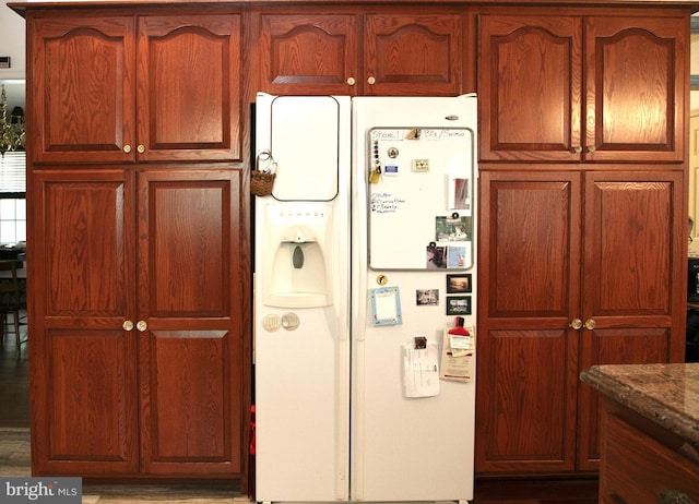 kitchen featuring stone counters and white fridge with ice dispenser