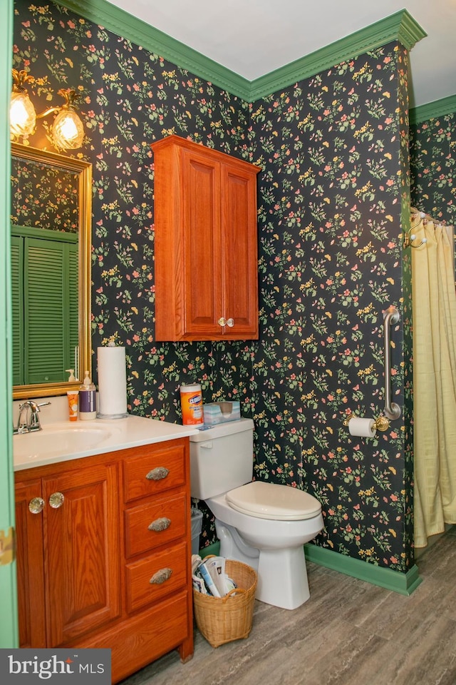 bathroom featuring hardwood / wood-style flooring, vanity, toilet, and ornamental molding