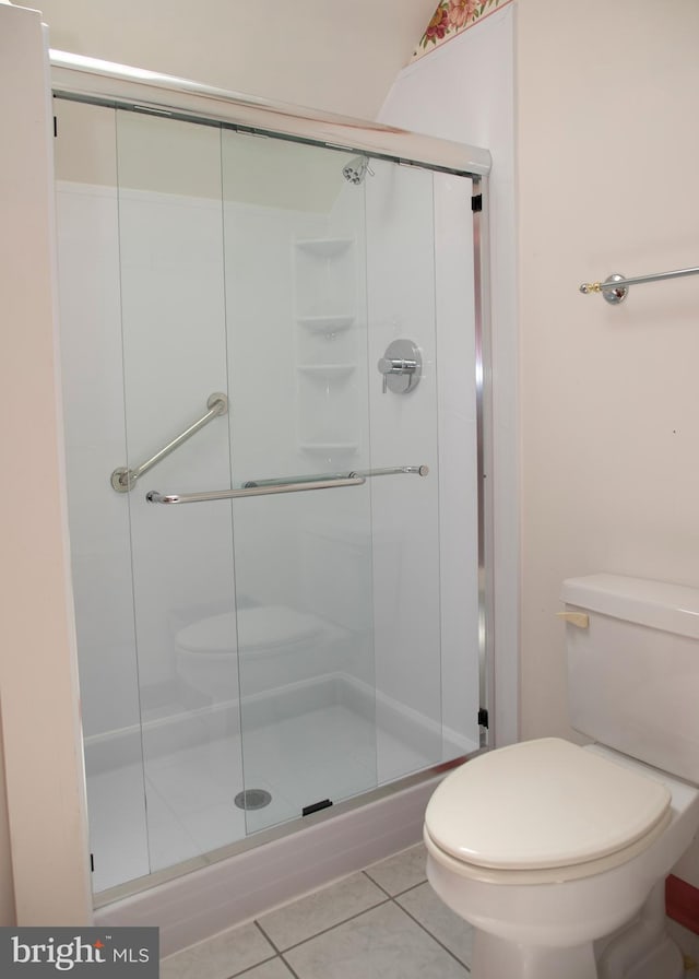 bathroom featuring tile patterned flooring, a shower with door, and toilet