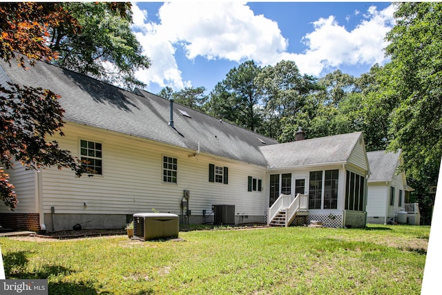 back of house featuring a sunroom, a lawn, and central AC