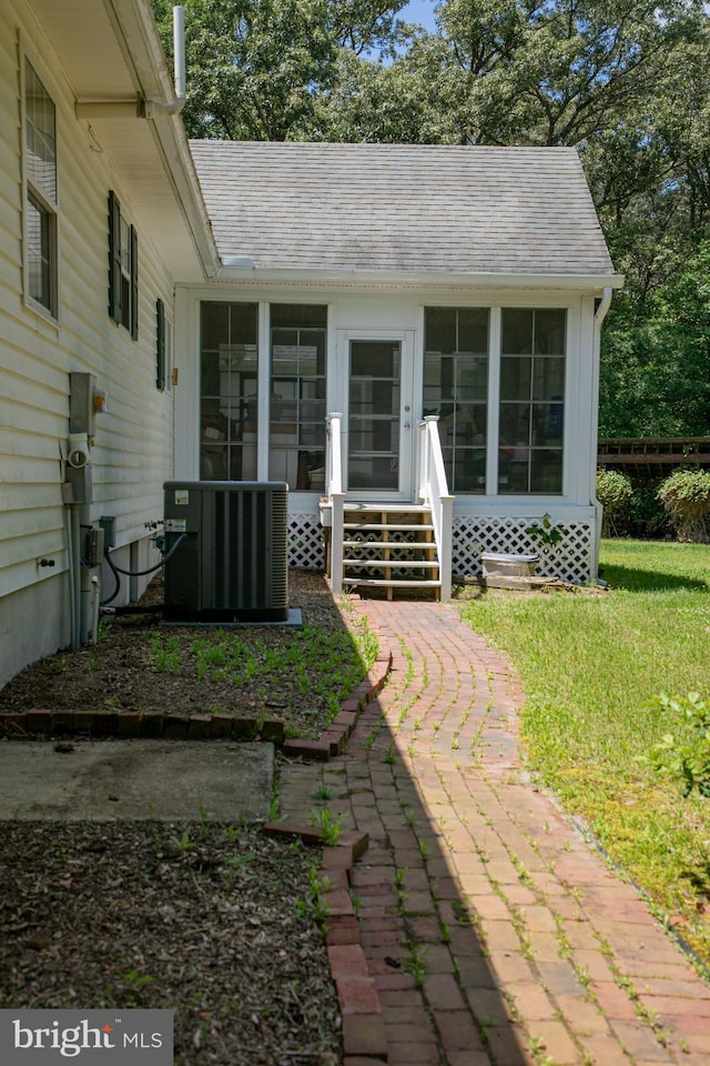 exterior space with central AC, a sunroom, and a yard